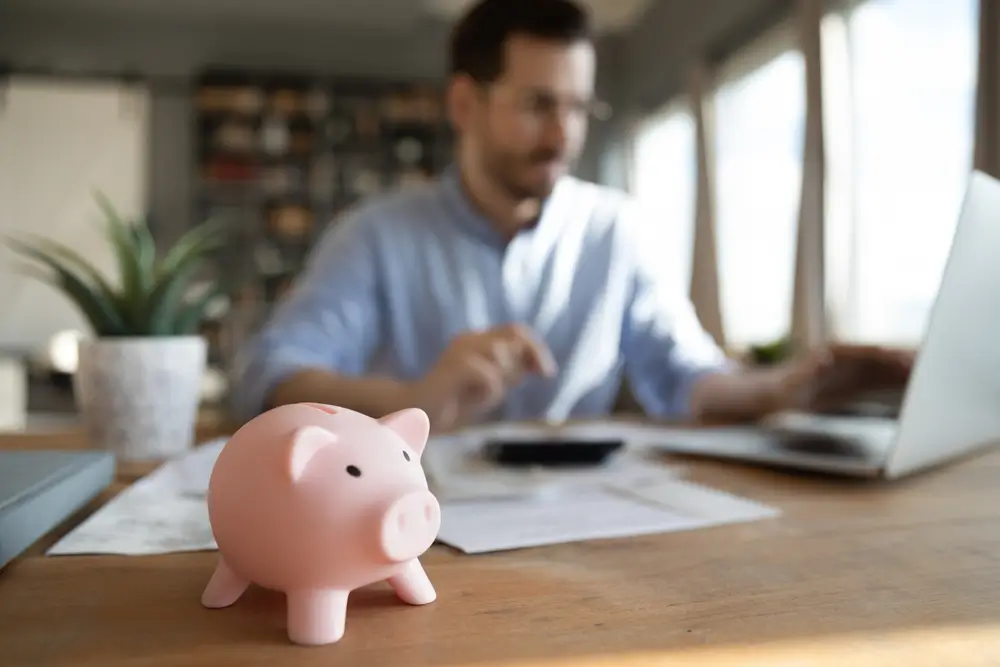 man at laptop with piggybank